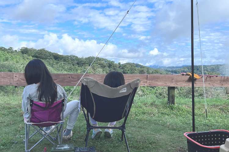 眺めのいいキャンプ場で、アウトドアチェアに座っている子ども