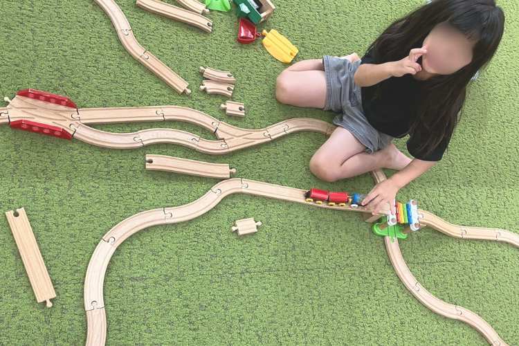 木製の列車とレールのおもちゃで遊ぶ子ども